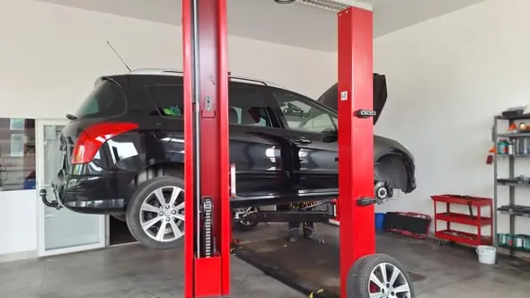 Fekete Peugeot a műhely emelőjén